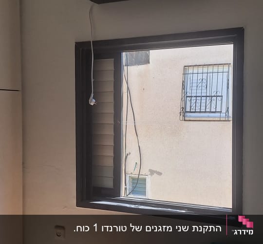 מזגן מותקן על קיר בחדר עם חלון פתוח